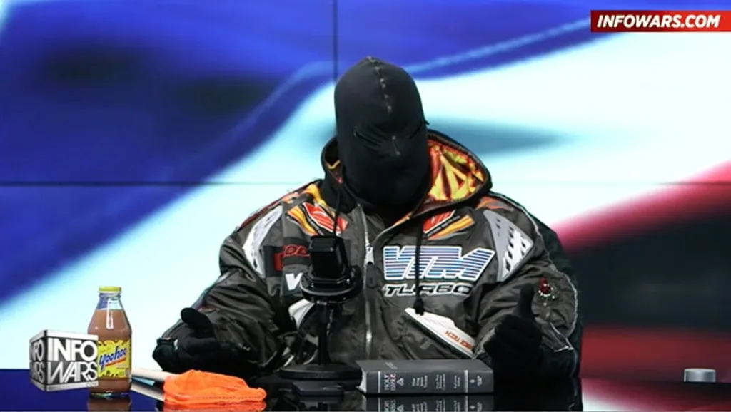 Ye on InfoWars, masked head to toe, a Yoo-hoo and a Bible on the desk. The teams that would have handled the fallout had already been cut.